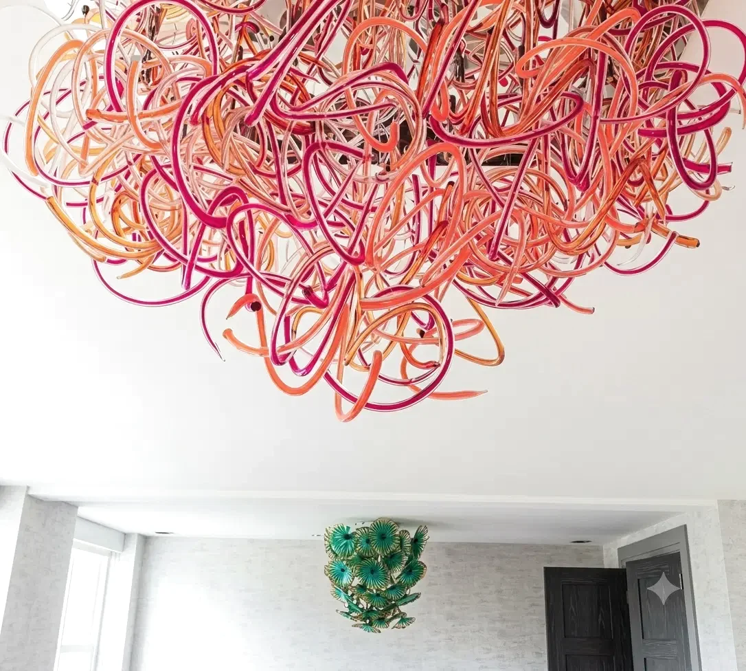 Sculptural orange and pink glass-loop chandelier mounted on a white ceiling