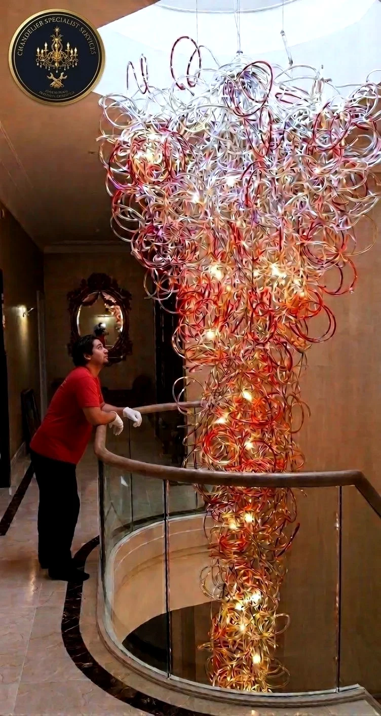 Chandelier specialist working beside a bespoke glass chandelier