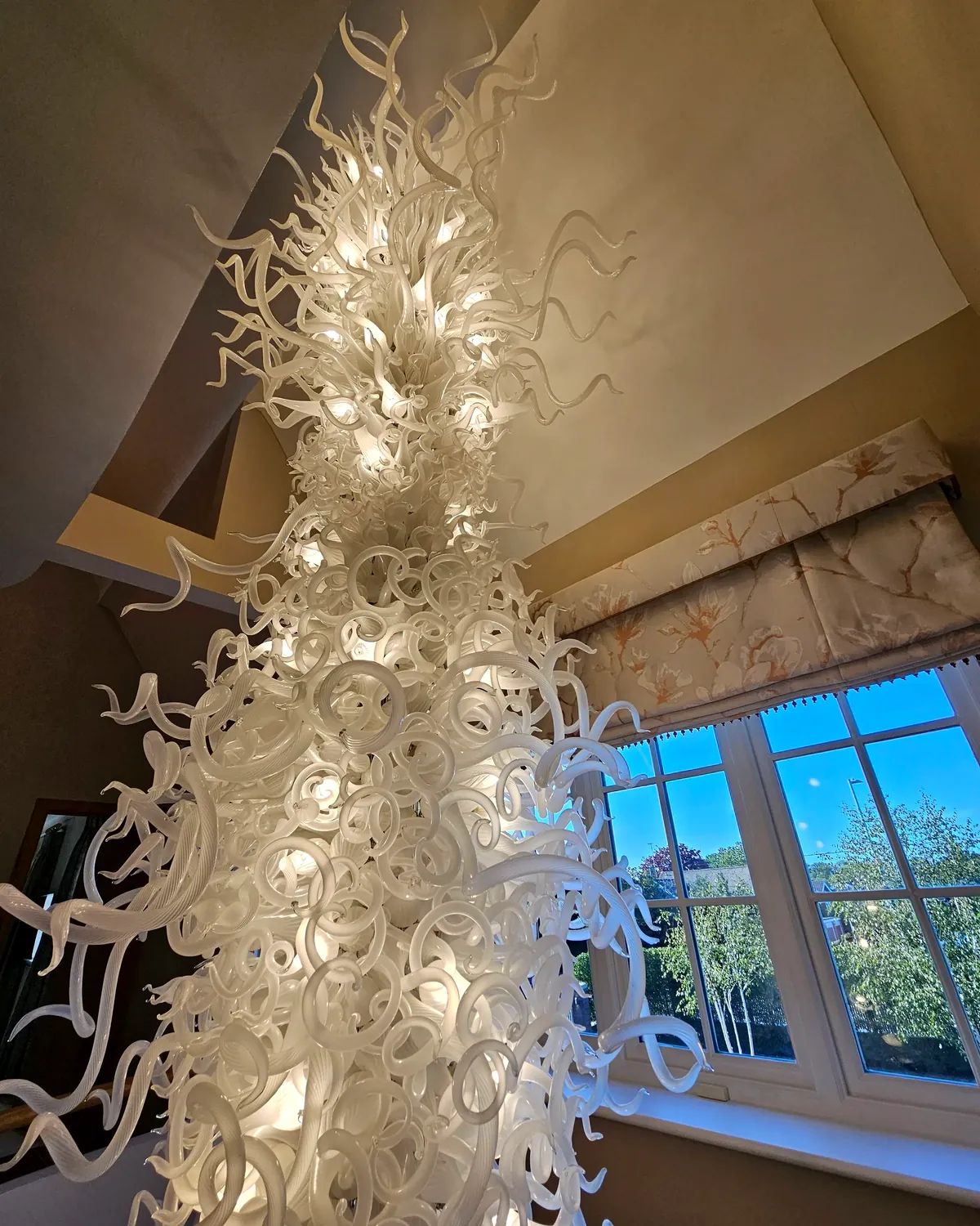 White hand-blown glass swirl chandelier viewed without a person in a residential staircase
