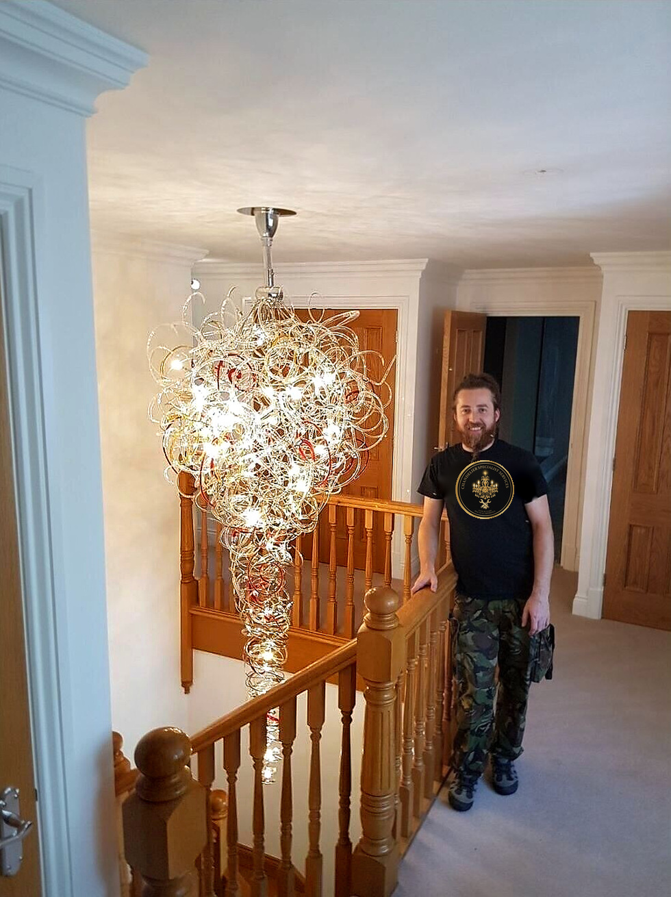 Specialist beside a large red and clear glass wire chandelier on a stairwell landing