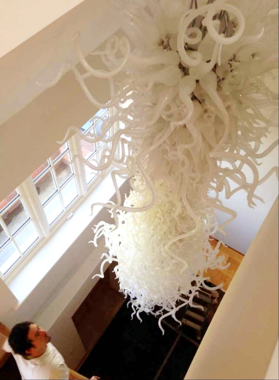 White hand-blown glass tendril cascade chandelier in a bright stairwell